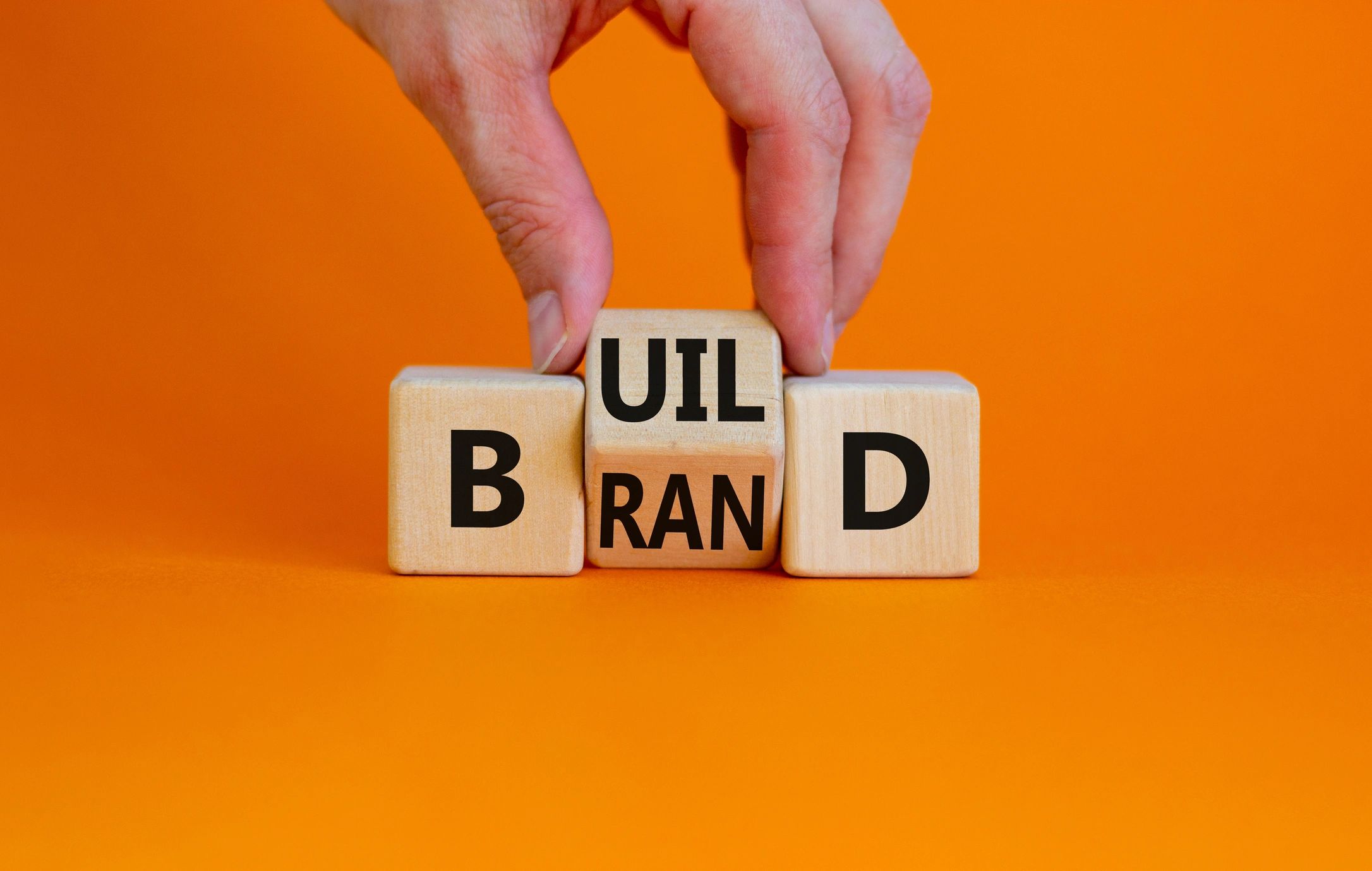 Build your brand symbol. Businessman turns wooden cubes